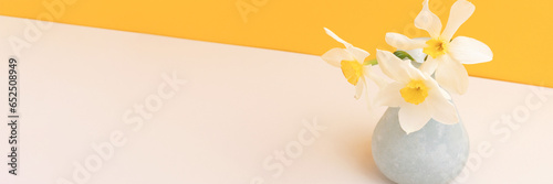 Banner with bouquet of white daffodil flowers in front of yellow background.