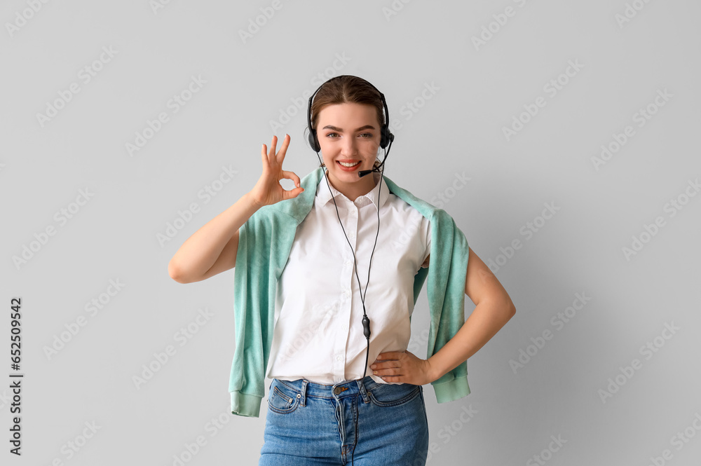 Fototapeta premium Female technical support agent showing OK on light background