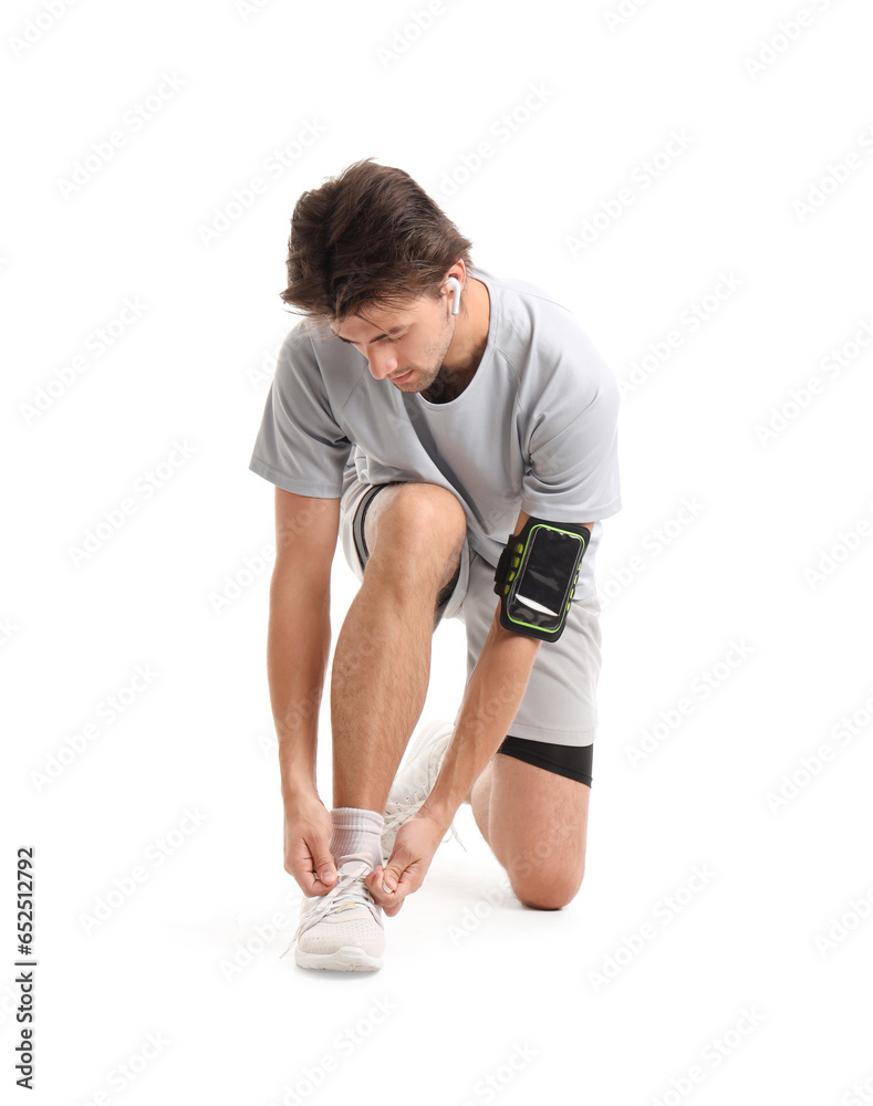 Young man in sportswear tying shoelaces on white background Young man in sportswear tying shoelaces on white background
