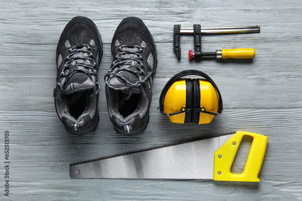 Set of construction tools and shoes on grey wooden background