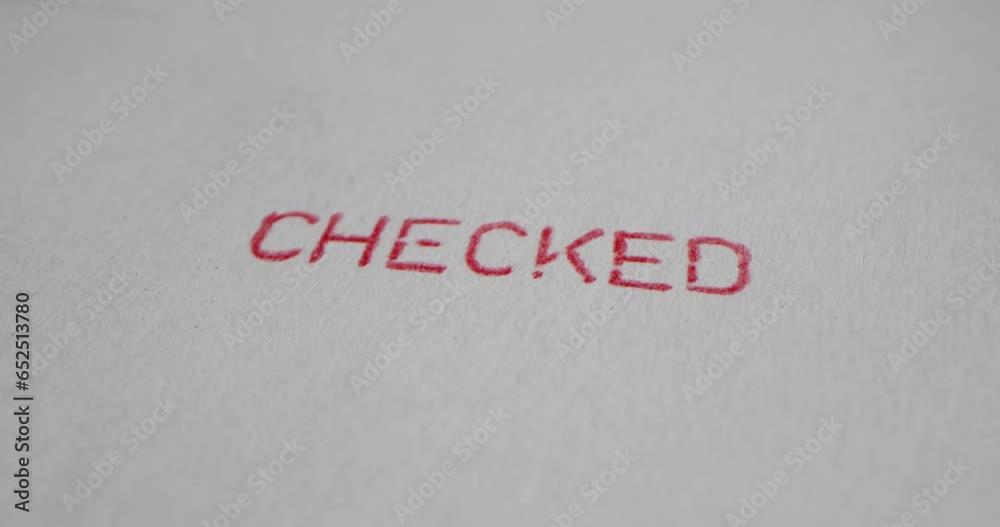 A stamp CHECKED is placed on a sheet of white paper, close-up A stamp CHECKED is placed on a sheet of white paper, close-up