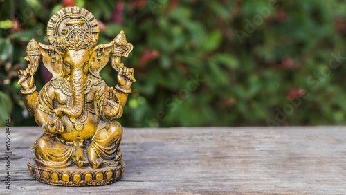Ganesha statue sitting in meditating yoga pose on a trunk. Copy space