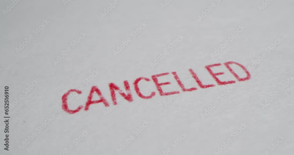 A stamp CANCELLED is placed on a sheet of white paper, close-up A stamp CANCELLED is placed on a sheet of white paper, close-up