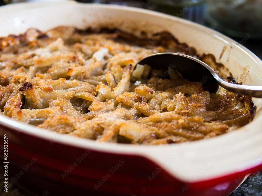 Φωτογραφία Traditional Swedish dish, Jansson's Frestelse, a casserole with potatoes, onion, anjovis and heavy cream, typically served at Christmas, here in a red pan with a spoon