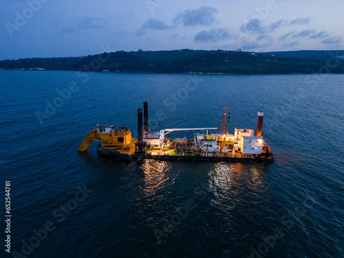 Canvas Print Aerial view of a dredge vessel with a dredging bucket, actively deepening the navigational fairway at sea, ensuring safe navigation