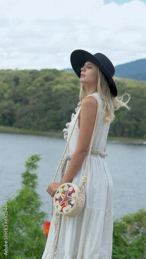 CAUCASIAN LATIN WOMAN WITH BLACK HAT ON COROTA ISLAND. LA COCHA LAGOON PASTO NARIÑO 4K vertical