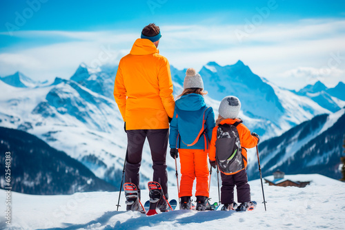 Back view of father and daughters enjoying ski day at top of the mountain. Winter holidays in family concept