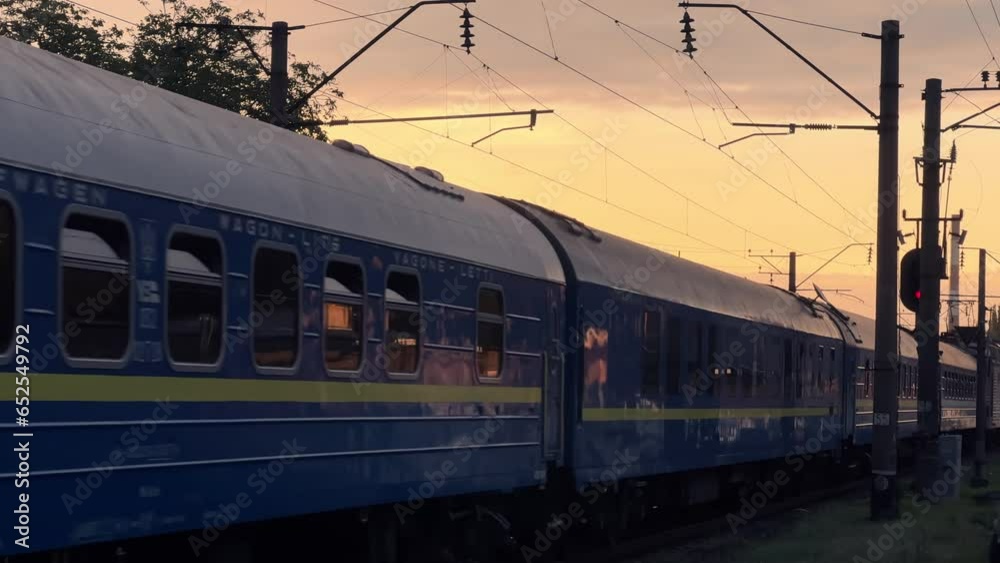 Passenger train travels through the countryside at a summer sunset. Long shot Passenger train travels through the countryside at a summer sunset. Long shot