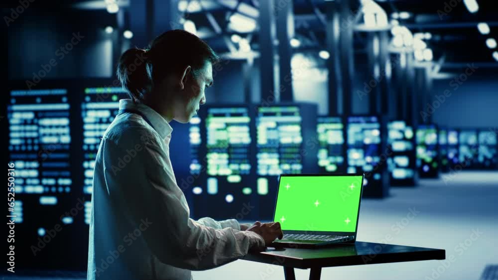 IT consultant running code on chroma key laptop, troubleshooting data center equipment. Cloud computing business executive using green screen device to examine servers and networking systems IT consultant running code on chroma key laptop, troubleshooting data center equipment. Cloud computing business executive using green screen device to examine servers and networking systems