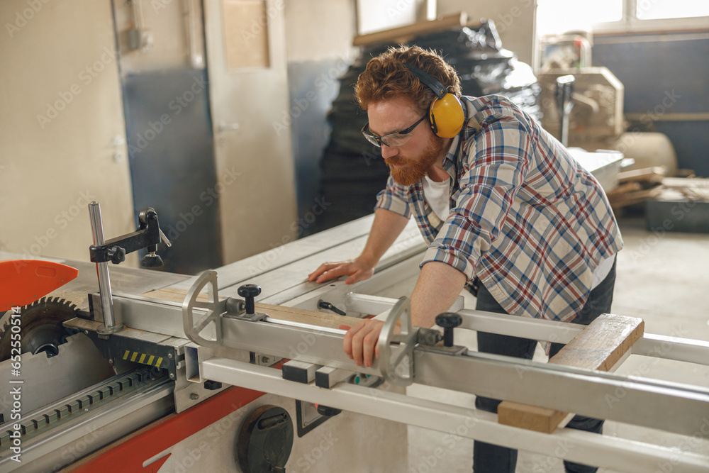 Professional carpenter cutting wooden board at sawmill carpentry manufacturing . Sawing machine Professional carpenter cutting wooden board at sawmill carpentry manufacturing . Sawing machine