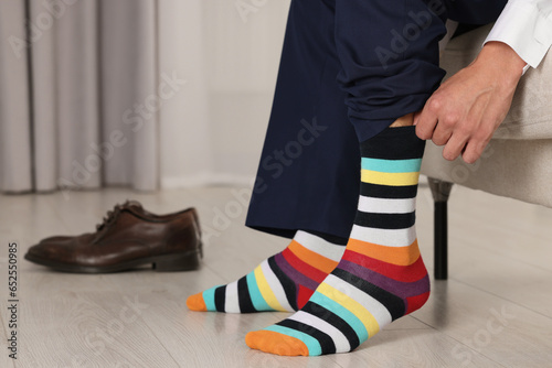 Man putting on colorful socks indoors, closeup