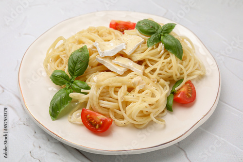 Delicious pasta with brie cheese, tomatoes and basil leaves on white textured table, closeup