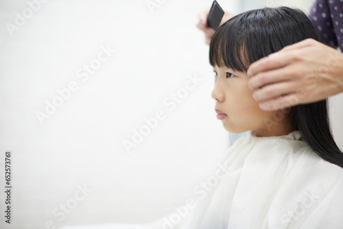 美容院で髪をカットされる子供の様子
