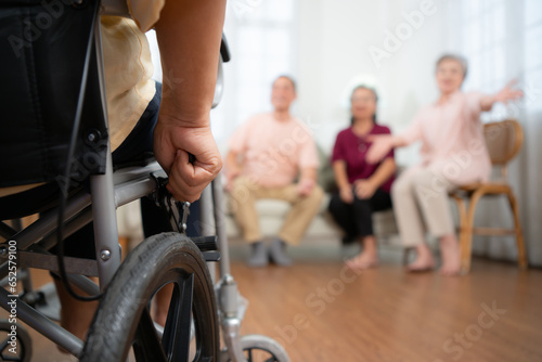Fototapeta Naklejka Na Ścianę i Meble -  Close-up of senior woman in wheelchair with her caregiver in background and elderly friends are waiting to welcome
