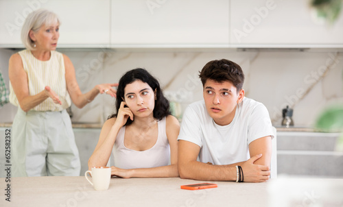 Portrait of an offended married couple in a home kitchen, which mature mother reprimand. Family conflict