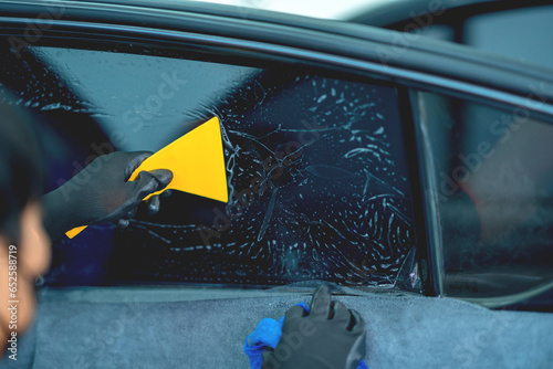 Technician uses equipment to install car window film.