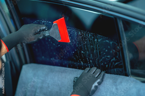 Technician uses equipment to install car window film.