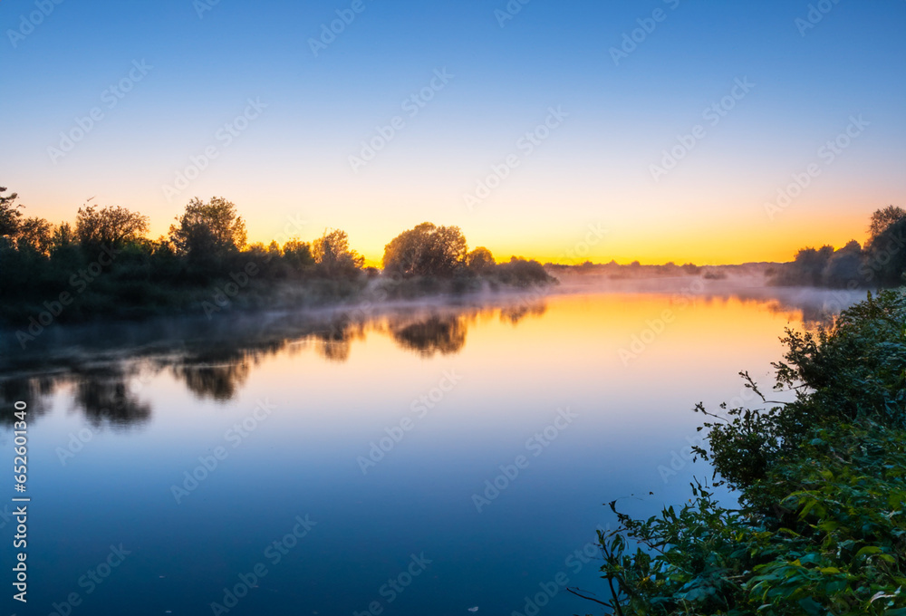 Riverside Scene At Dawn. Sunrise over the river. Fog on Water.