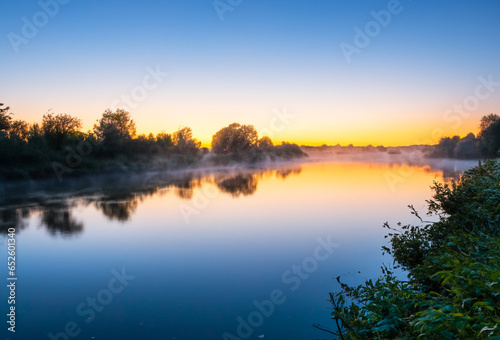 Riverside Scene At Dawn. Sunrise over the river. Fog on Water.