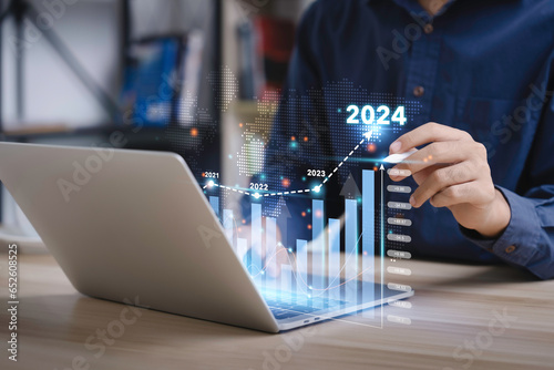 Businessman analyzes the graph of trend market growth in 2024 and plans business growth and profit increase in the year 2024. plan finances of the business
