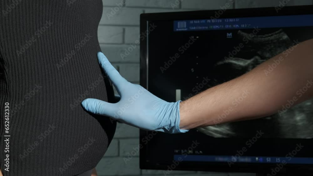 Hand in gloves by pregnant belly. A view of hand in rubber glove try to