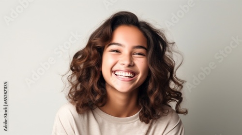 A portrait captures the genuine joy of a teen girl with a bright smile.