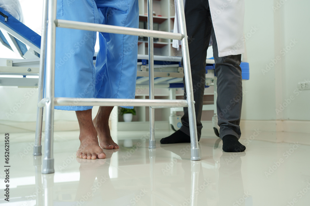Physical therapist helps a male patient use a walker to practice walking. Support yourself from recovery from sore legs and ankles. Physical therapy service concept. Physical therapist helps a male patient use a walker to practice walking. Support yourself from recovery from sore legs and ankles. Physical therapy service concept.