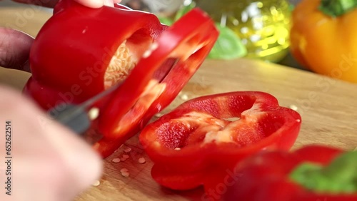 Close-up of male hands cutting red pepper on a wooden board. Slicing fresh vegetables with a knife.

