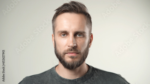 Handsome person look at camera close up. Young adult man face portrait. Stylish 30s guy on isolated white background. Attractive male model. Modern millennial people. Brutal bearded style. Barber shop