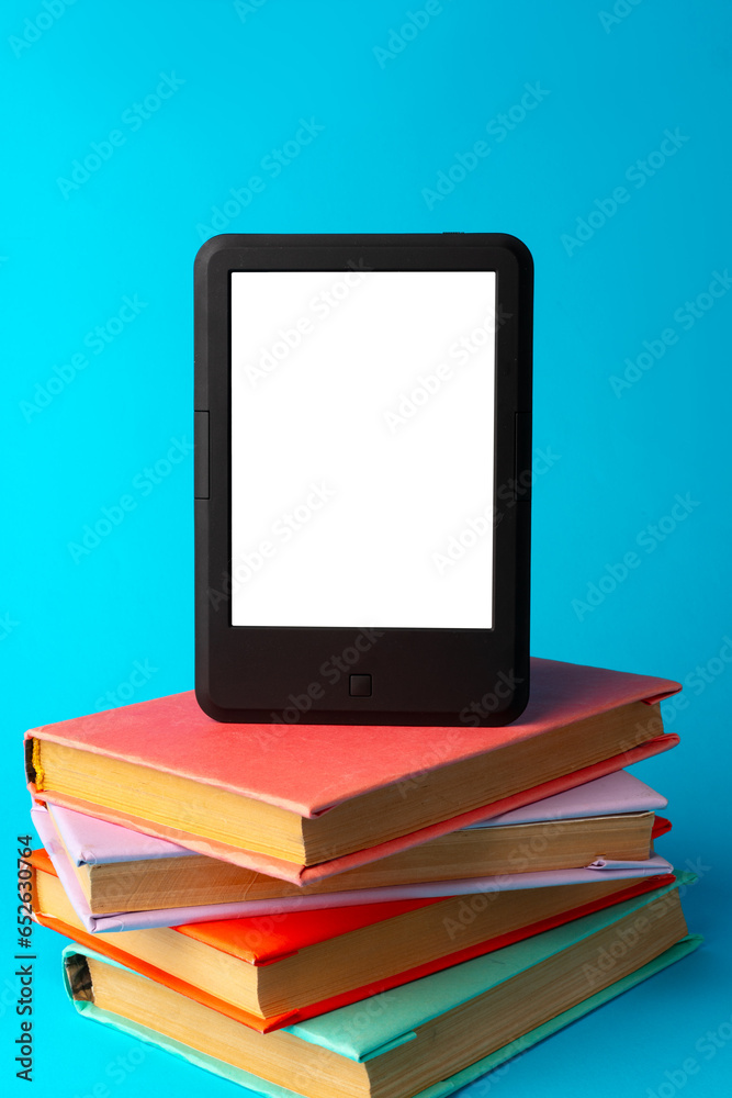 Modern e-book on stack of hardcover books on blue background Modern e-book on stack of hardcover books on blue background