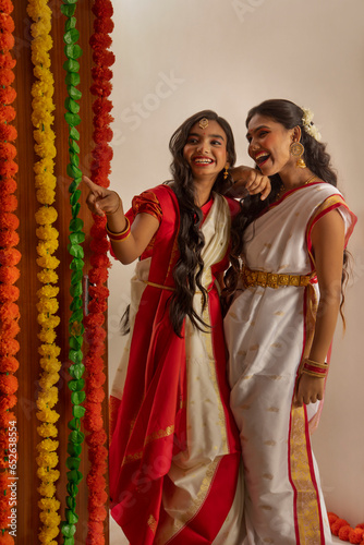 Portrait of two Bengali sister in traditional outfit standing together at home on the occasion of Durga Puja