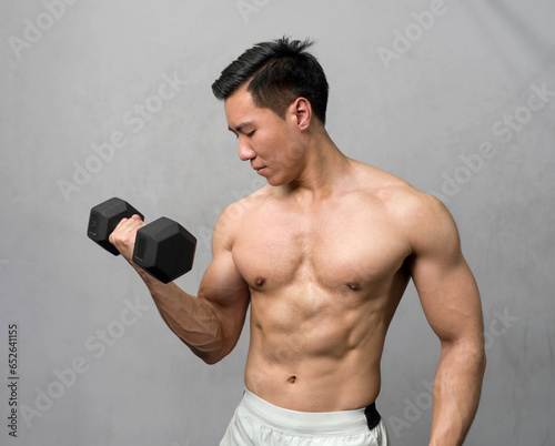A physically fit man engaged in a workout session at a modern gym  determinedly lifting a heavy dumbbell as he strives for strength and wellness.