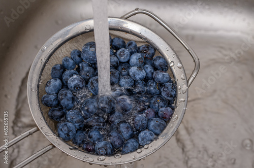 Mycie owoców pod strumieniem zimnej wody z kranu, borówka amerykańska 