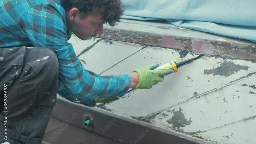 A carpenter applying sealant into seams of wooden boat hull planks Stock ビデオ Adobe Stock