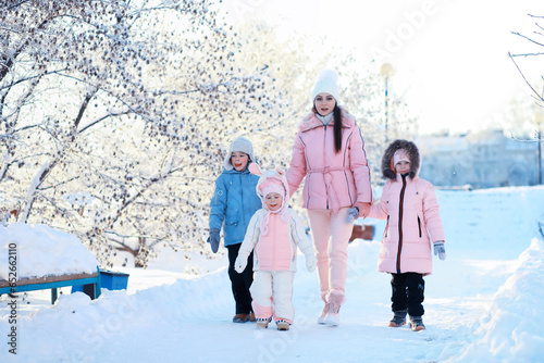 Family with children play snowy winter games in the park. Winter holidays and family vacation. Winter walk on the street on a sunny frosty day.