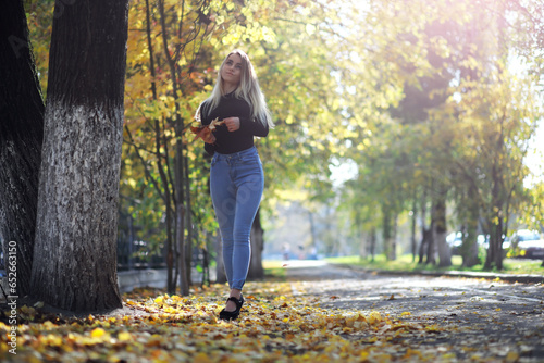Young beautiful girl for a walk in a summer park. Leaf fall in the city park. Beginning of autumn. September.