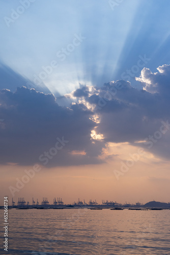 huge white sun-rays behind cloud, calm peach pink blue sky 