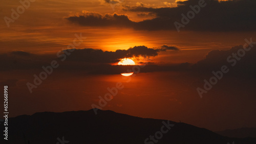 Red sky with sun in the middle, beautiful sunrise with clouds and mountain