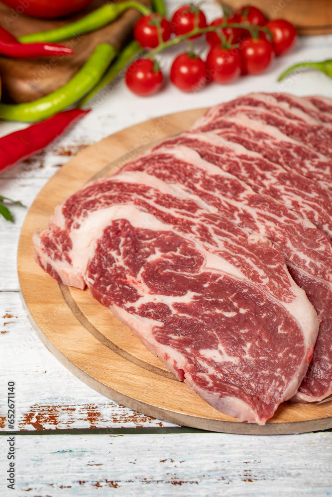 Raw fresh meat ribeye steak on wood background. Raw wagyu ribeye with herbs and spices. Close up