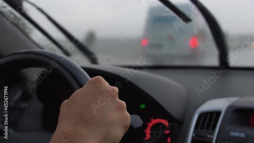 Car Dashboard and Female Hands Holding Steering Wheel When Driving in Heavy Rain © maradek