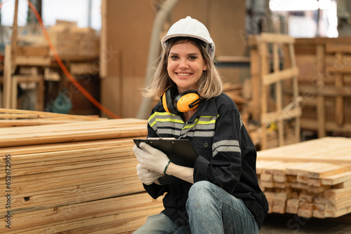 Caucasian technician craft woman holding clipboard with stock timber background at wood factory 