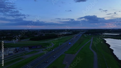 Under dramatic and moody sunset sky vehicles travel along Highway A15 at Alblasserdam photo