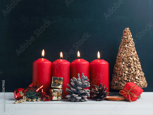 Fourth Advent candles burning with Christmas decoration on a chalkboard