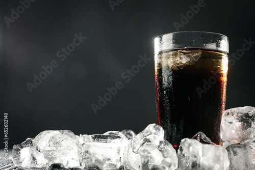 Coca cola in glass with ice on dark background, space for text
