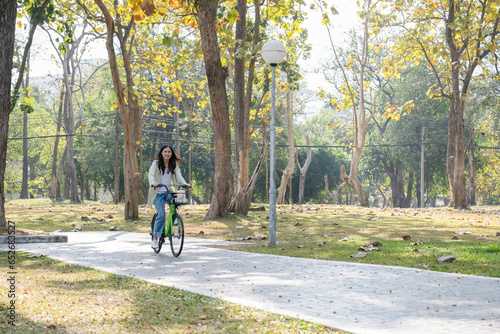 Happy woman riding bicycle at park. © MIND AND I