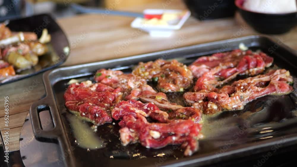 Cooking japanese food delicious suki shabu and grill on bbq pan or barbeque pan. Close up of hotpot shabu while using chopsticks putting meat beef sliced to cook in hot pot pan. Cooking japanese food delicious suki shabu and grill on bbq pan or barbeque pan. Close up of hotpot shabu while using chopsticks putting meat beef sliced to cook in hot pot pan.