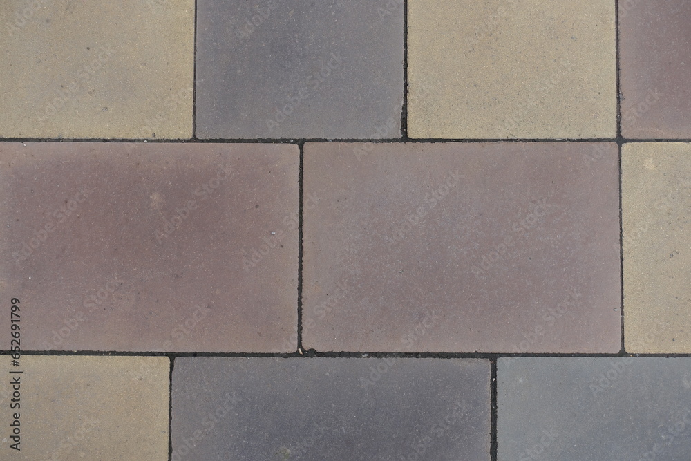 Fototapeta premium Closeup of pavement made of pink, yellow, brown and grey concrete blocks
