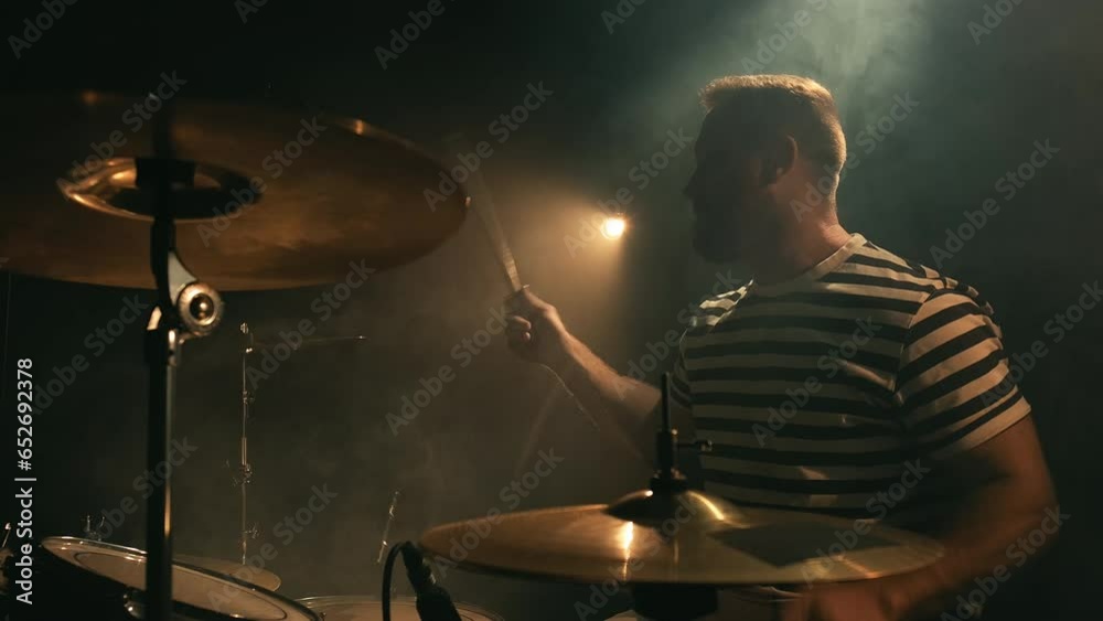 Male drummer plays a drum kit in a dark room full of smoke. Music or song recording, creation. Music band repetition