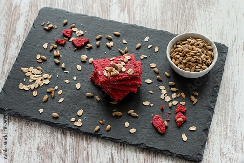 Healthy Snack Cracker or Biscuit with Seeds and Beetroot Top View on a Stone Plate with Oat Flakes on Wooden Background, Healthy Eating or Dieting Concept