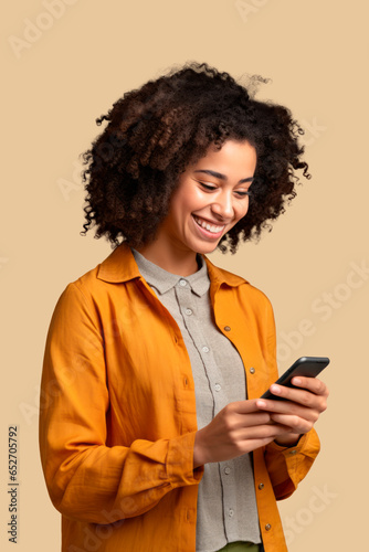 woman of color with curly hair looking at her smartphone with beige background